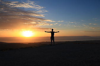 Silhouette of Person with Arms Outstretched at Sunrise