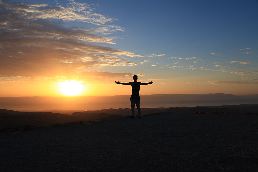 Silhouette of Person with Arms Outstretched at Sunrise