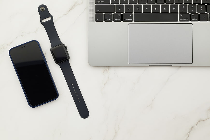 Flat lay of smartphone, smartwatch, and laptop on marble desk