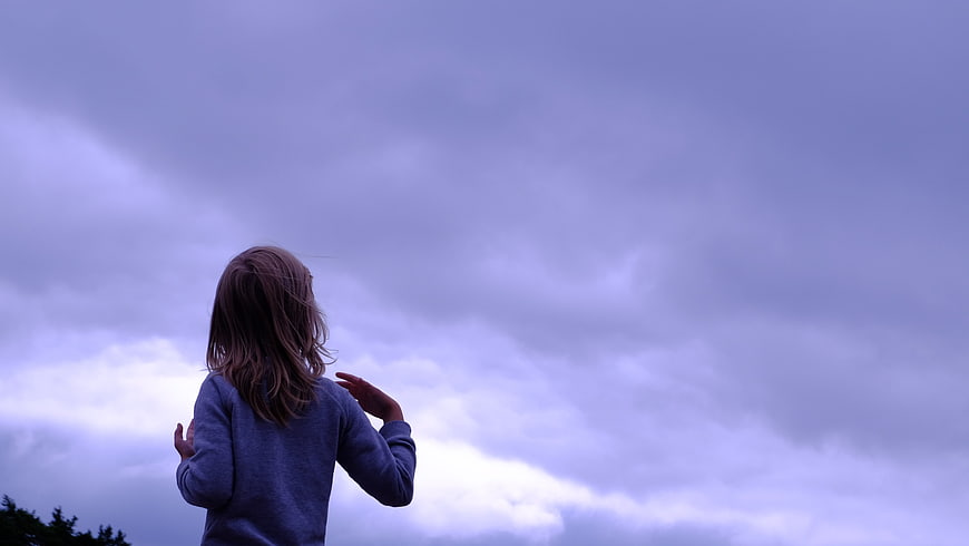 Girl Looking Up at Cloudy Sky from Behind
