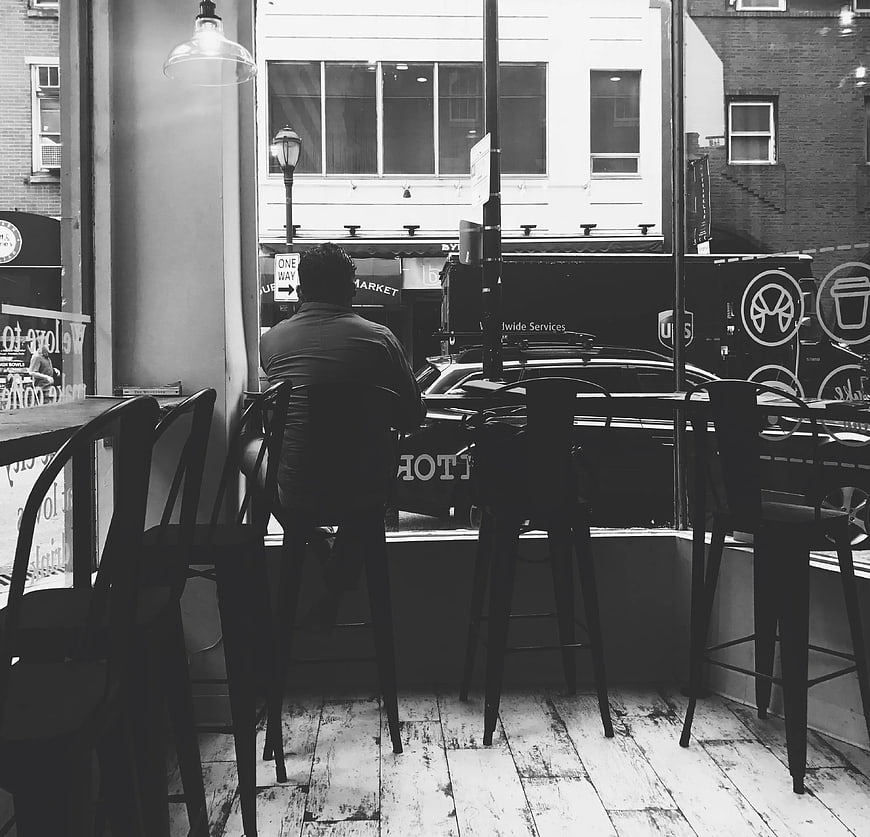 Man sitting in cafe looking out window at street