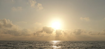 Sunset over ocean with clouds and golden light reflection