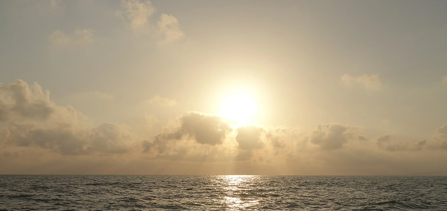 Sunset over ocean with clouds and golden light reflection