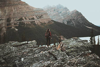 Woman Hiker Standing on Rocky Mountain Outcrop Overlooking Lake