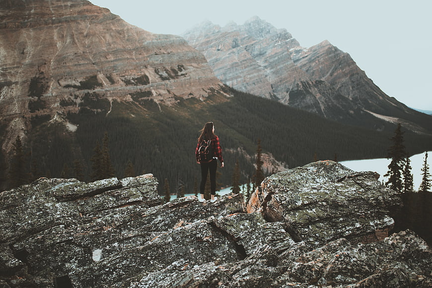 Woman Hiker Standing on Rocky Mountain Outcrop Overlooking Lake