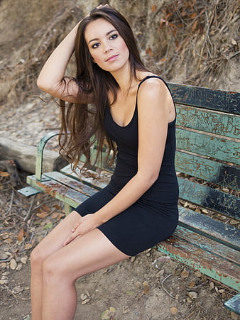 Woman in Black Dress Sitting on Weathered Park Bench