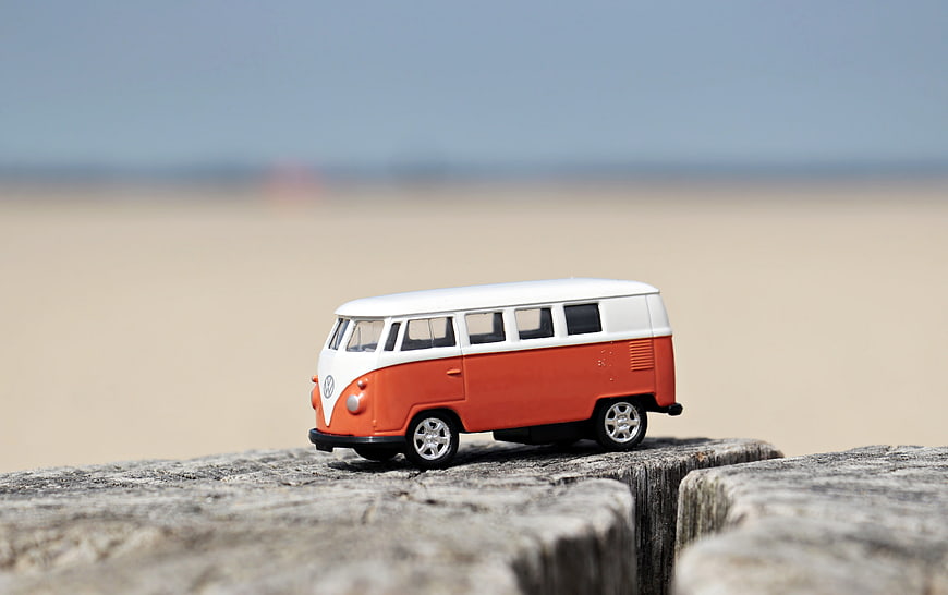 Retro Orange and White VW Camper Van Toy on Wooden Log
