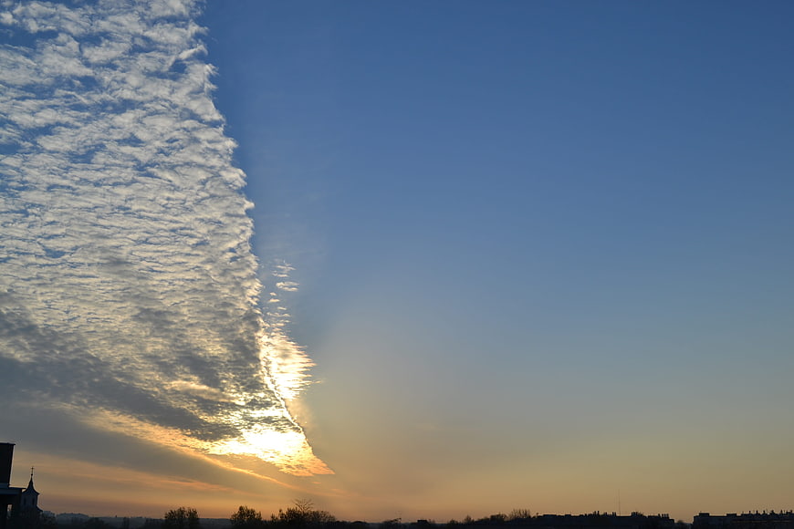 Dramatic sunrise with textured clouds over city silhouette