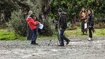 Film crew filming outdoor scene in rural orchard setting