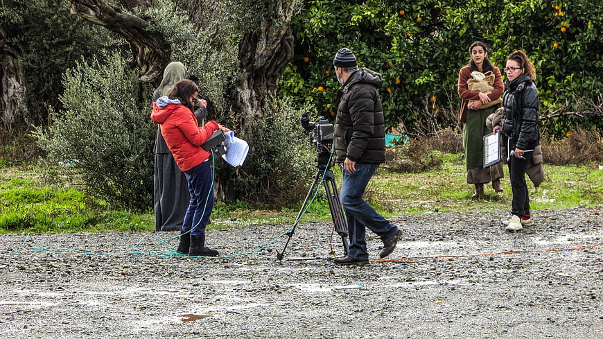 Film crew filming outdoor scene in rural orchard setting