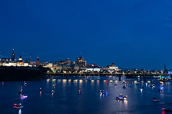 Ottawa skyline at dusk with illuminated Parliament and boats on river