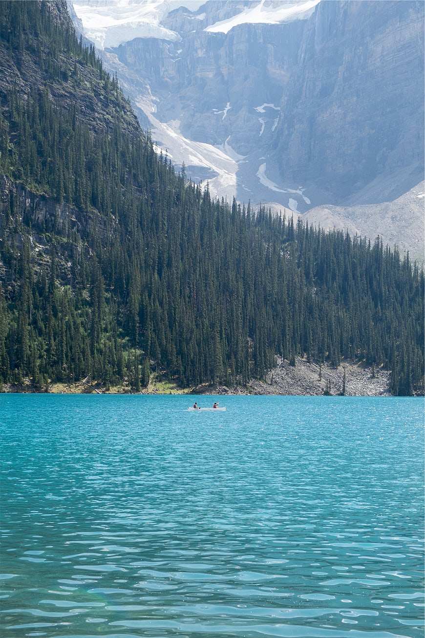 Turquoise glacial lake with canoe and mountain backdrop