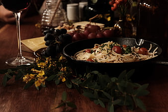 Rustic Pasta Dish with Wine and Grapes on Wooden Table