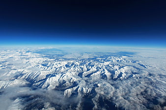 Aerial View of Snow-Covered Mountain Range Above Clouds