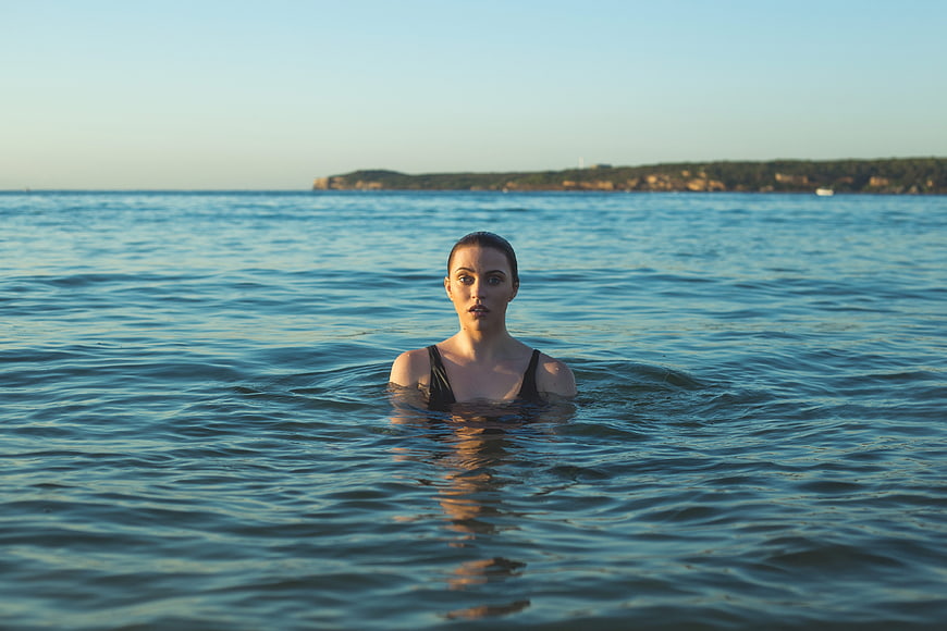 Woman Swimming in Ocean at Sunset