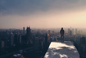 Man standing on rooftop overlooking hazy city skyline