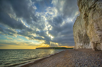 Dramatic sunset over white cliffs and pebble beach