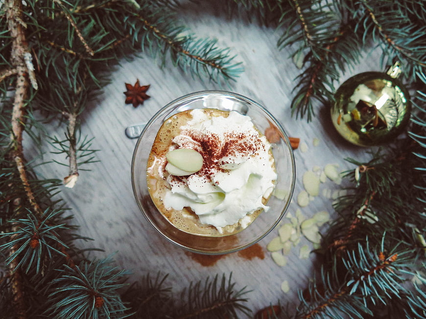 Overhead view of festive coffee with whipped cream and pine branches