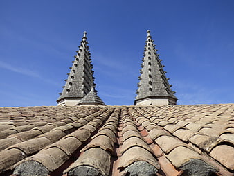 Terracotta roof tiles with stone pinnacles against blue sky