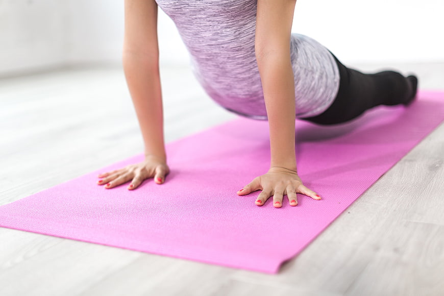 Woman doing yoga plank pose on pink mat