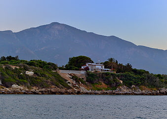 Coastal house with mountain backdrop and calm sea