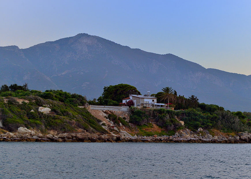 Coastal house with mountain backdrop and calm sea