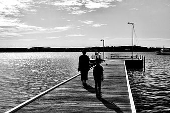 Silhouettes of Woman and Child Walking on Wooden Pier