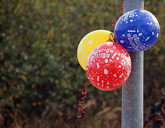 Three Happy Birthday Balloons Tied To A Metal Pole