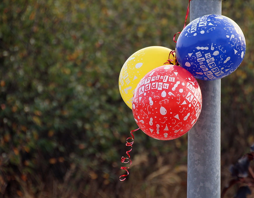 Three Happy Birthday Balloons Tied To A Metal Pole
