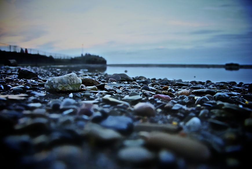 Low angle view of pebbles on a rocky beach at dusk