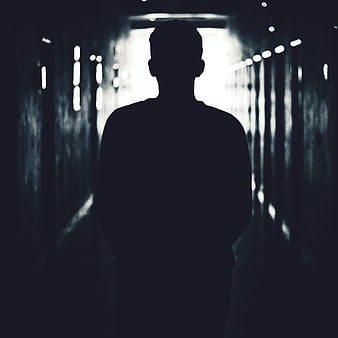 Silhouette of a man standing in a dark tunnel