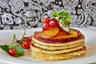 Stack of pancakes with apricots and red currants