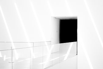 Minimalist white interior with diagonal light beams and glass railing