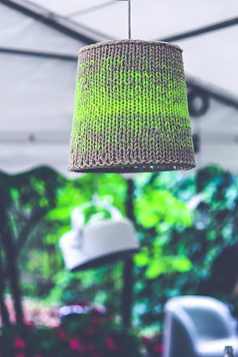 Hand-knitted green and brown lampshade hanging in garden