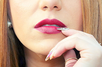 Close-up of woman's lips with red lipstick and manicured nails