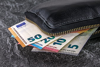 Black leather wallet with euro banknotes on dark textured surface