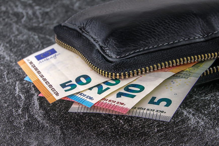 Black leather wallet with euro banknotes on dark textured surface