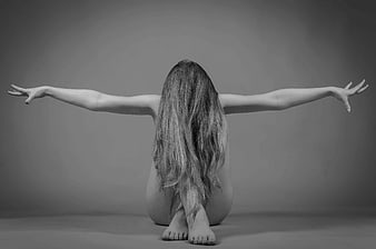 Black and white artistic portrait of a woman with long hair and outstretched arms