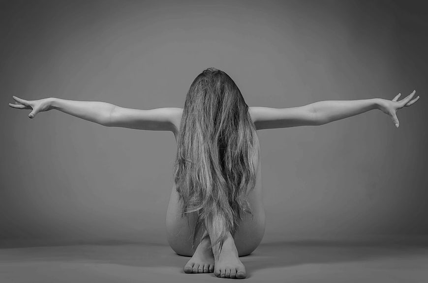 Black and white artistic portrait of a woman with long hair and outstretched arms