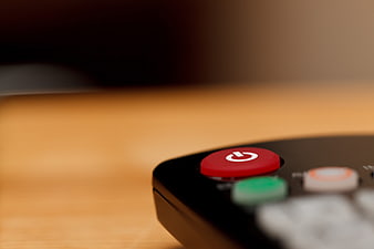 Close-up of red power button on black remote control