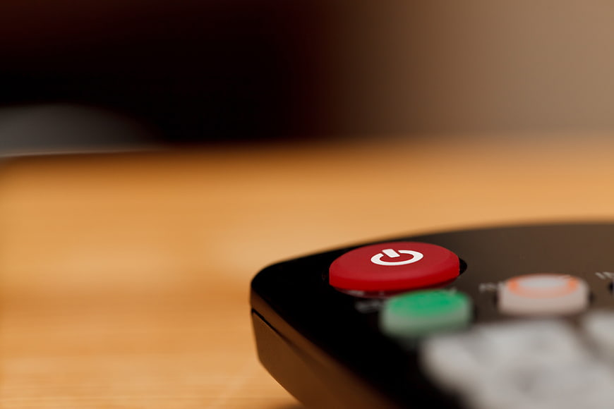 Close-up of red power button on black remote control