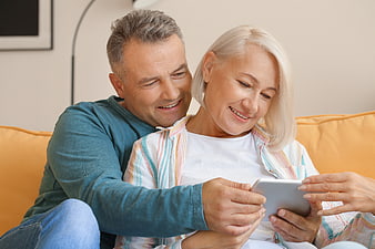 Happy Senior Couple Using Tablet on Sofa