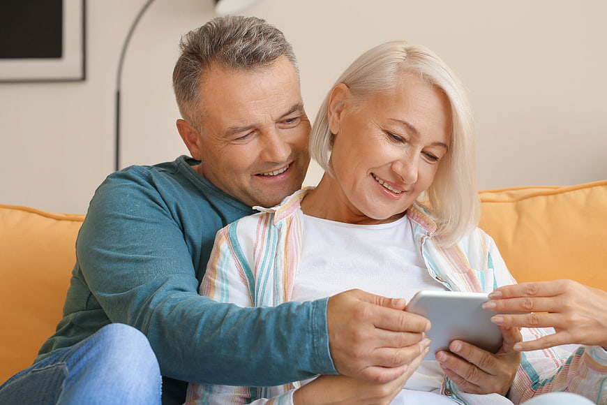 Happy Senior Couple Using Tablet on Sofa