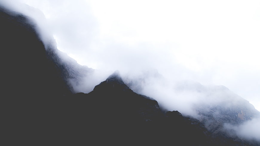 Dark Mountain Peaks Shrouded in Thick White Fog