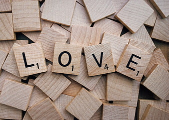 Wooden Scrabble Tiles Spelling Love on Scattered Background