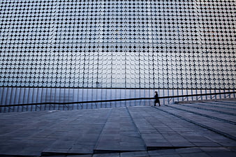 Man Walking Past Modern Geometric Building Facade