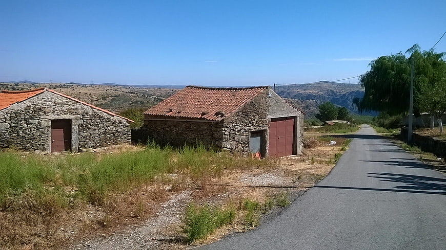 Rustic stone houses with red tile roofs on rural road