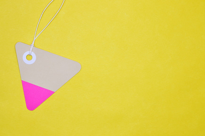 Triangular kraft paper price tag with pink accent on yellow background