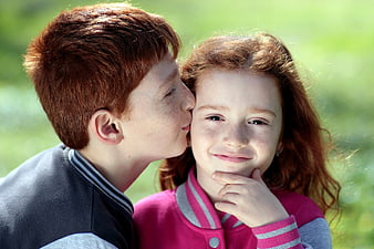Redhead siblings kissing on cheek outdoors
