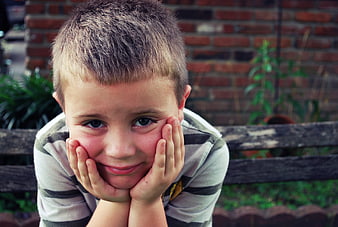 Young boy resting chin on hands with thoughtful expression
